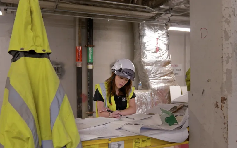 a woman in a hardhat looks over construction plans