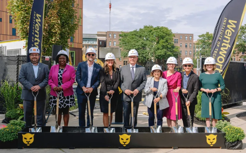 a group of people wearing hard hats and holding shovels
