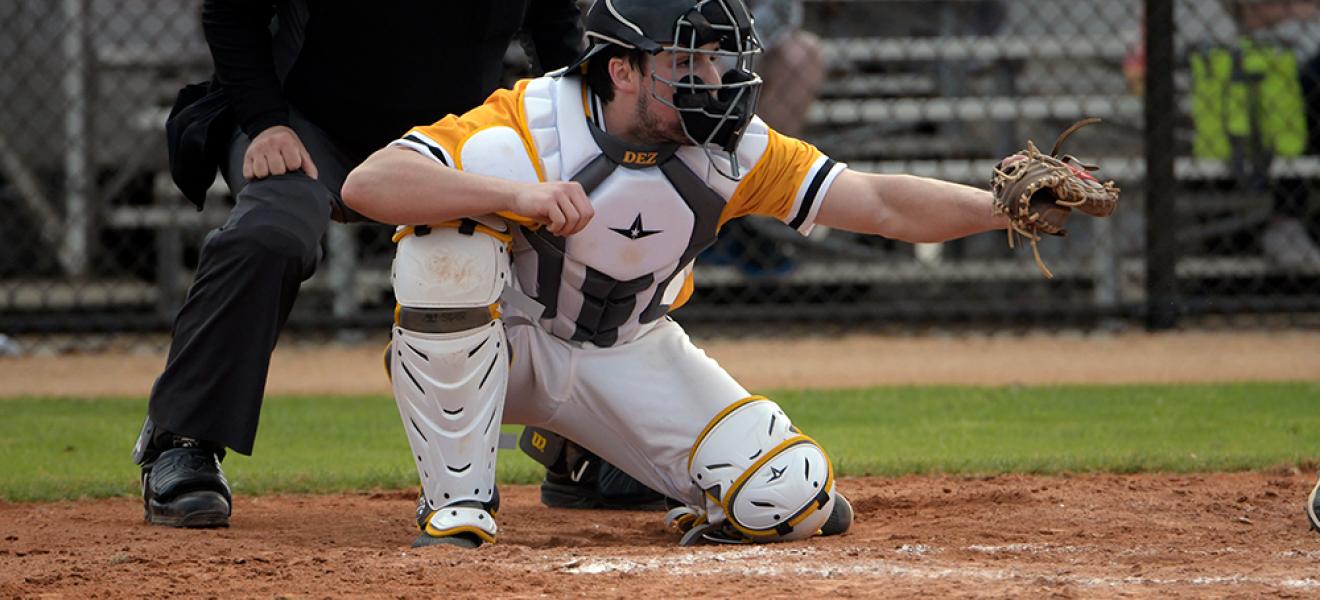 man playing baseball in catcher's uniform