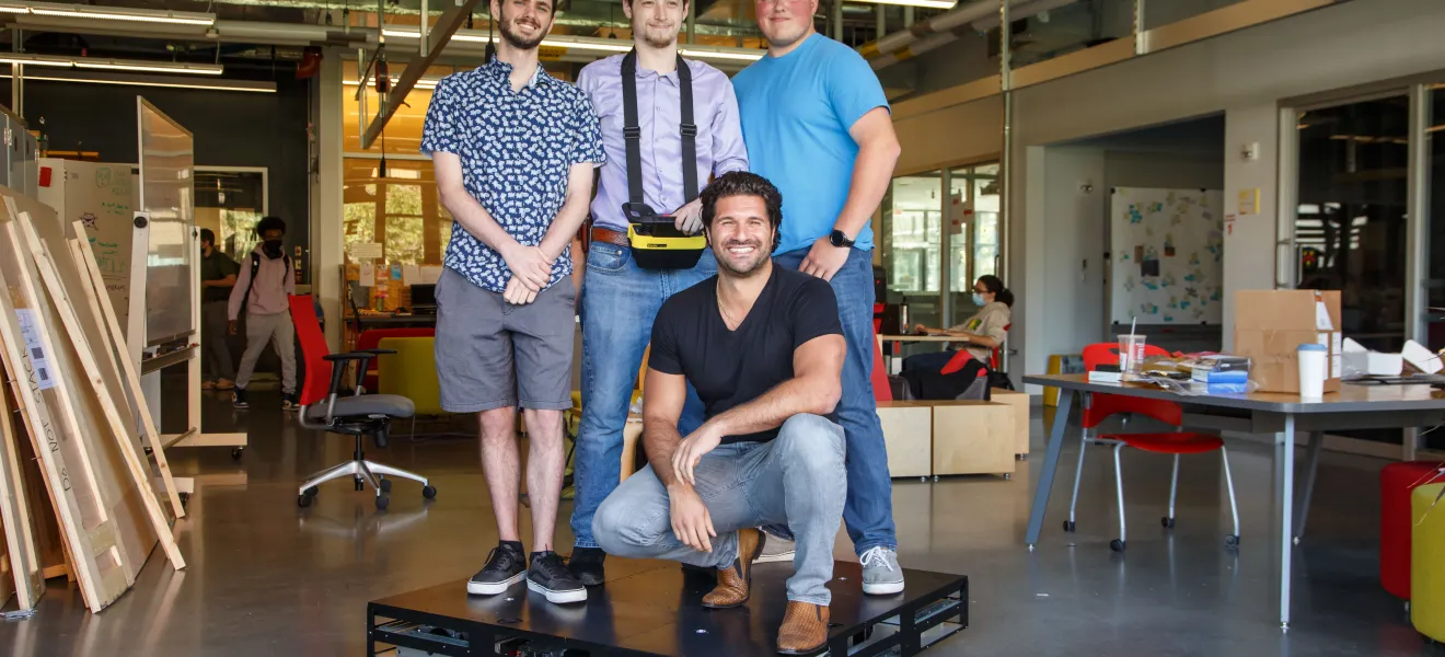 students and alum working with robot