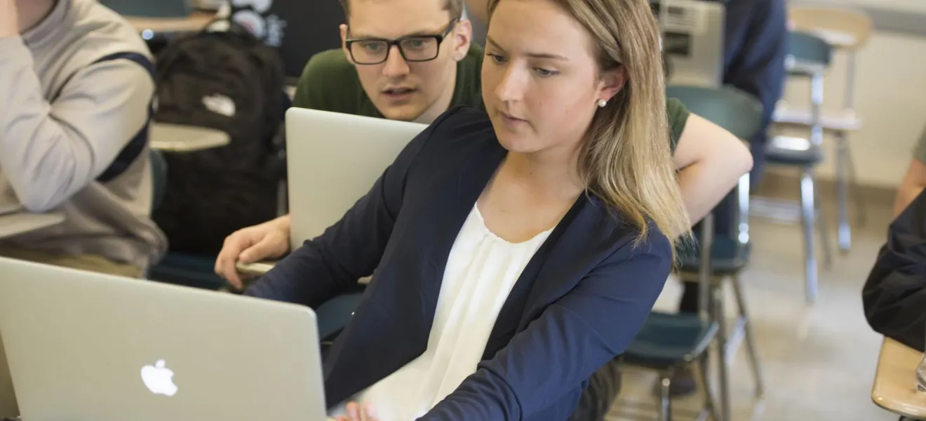 Two students discuss their project together in the classroom