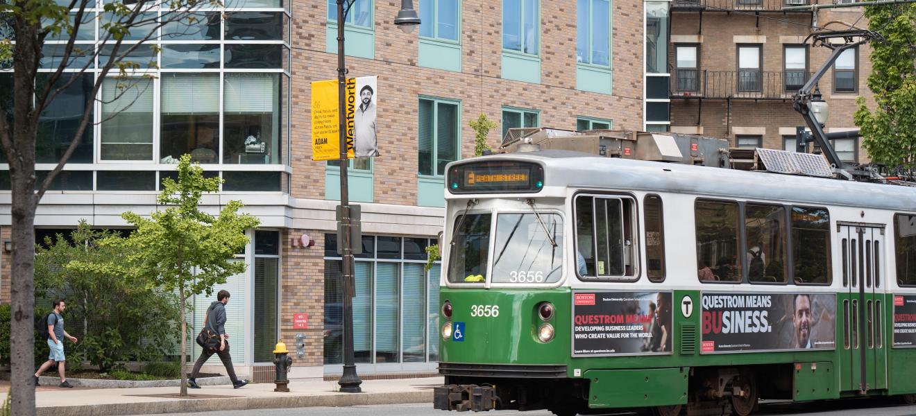 a green train moves past a building