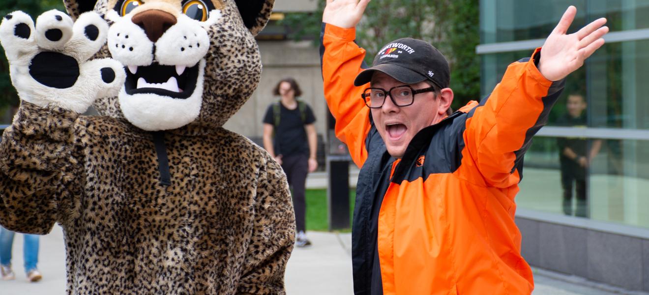 man posing with person in a leopard mascot costume