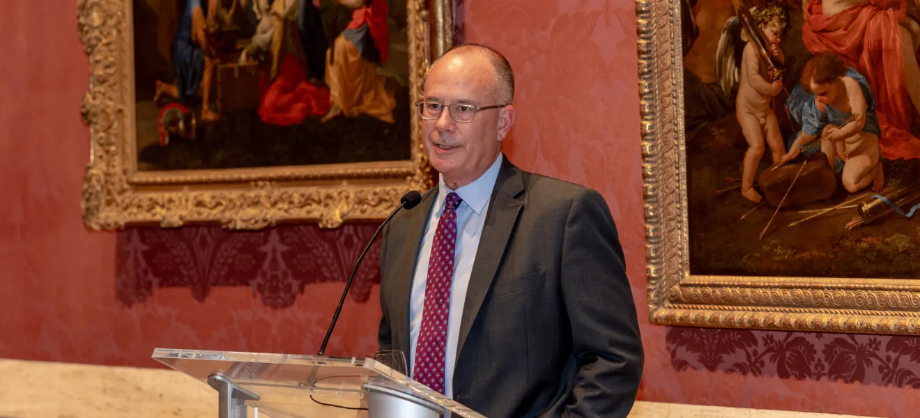 man speaking in a room with oil paintings