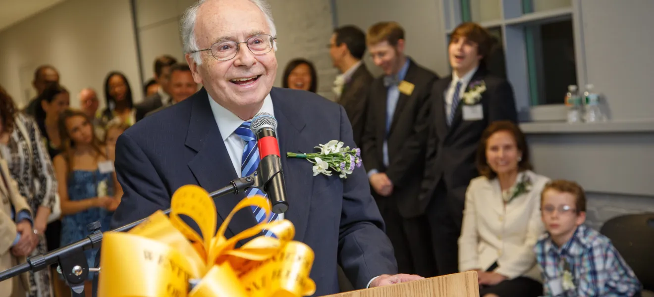 a smiling man speaking at a podium