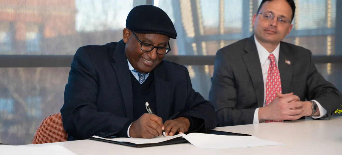 a man smiling as he signs a piece of paper