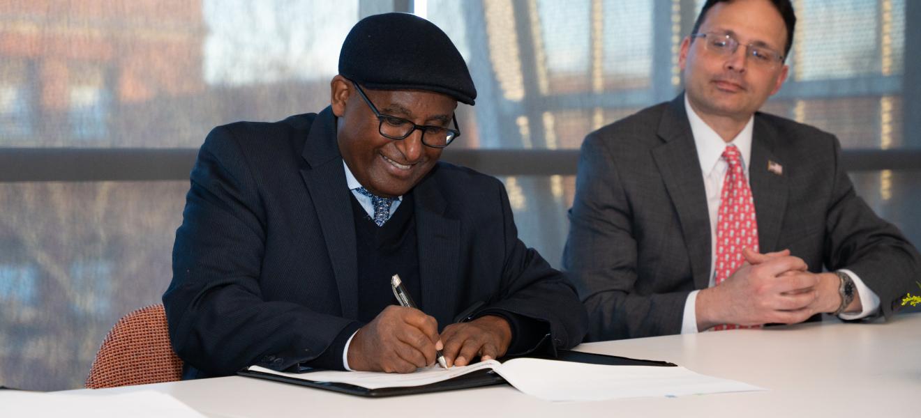 a man smiling as he signs a piece of paper