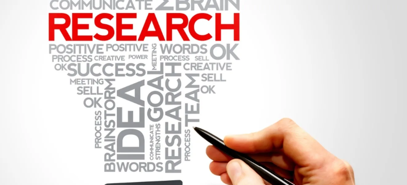 a hand holding a pen writes words including "research"