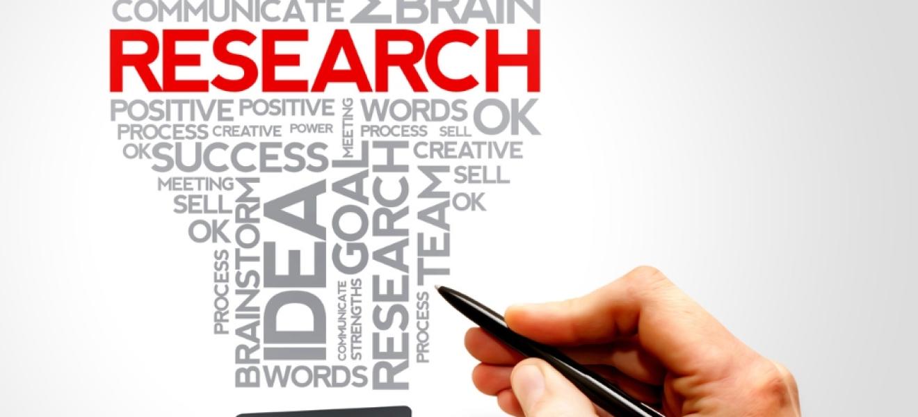 a hand holding a pen writes words including "research"