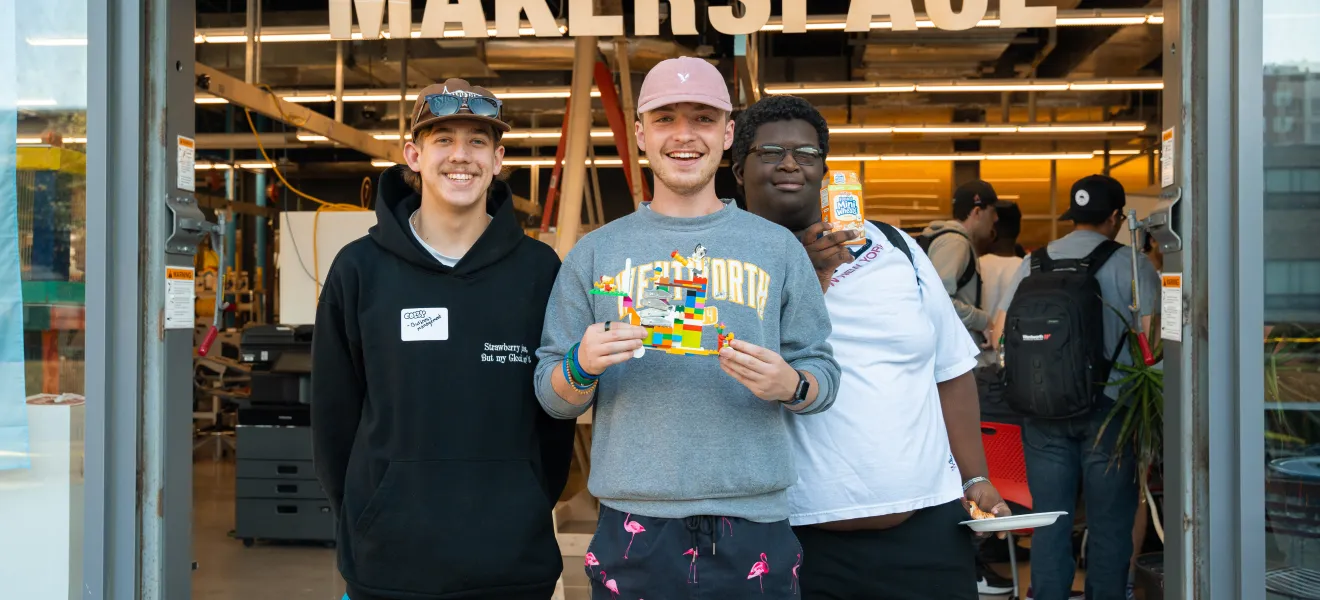 three students holding a lego creation
