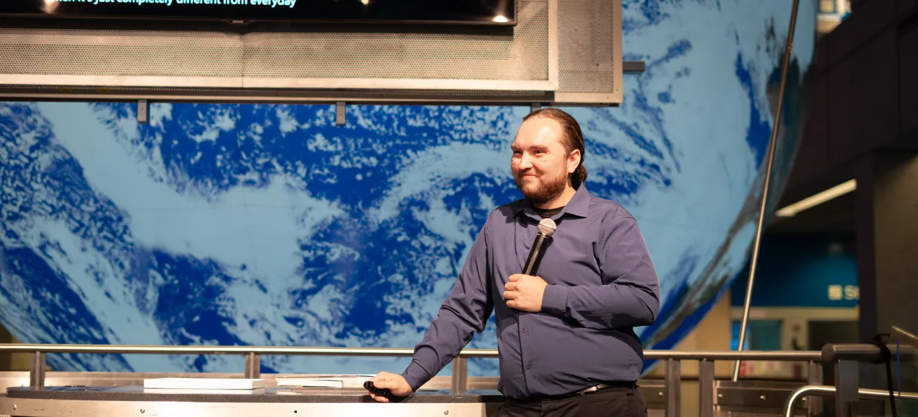 man stands in front of a large projection of planet earth