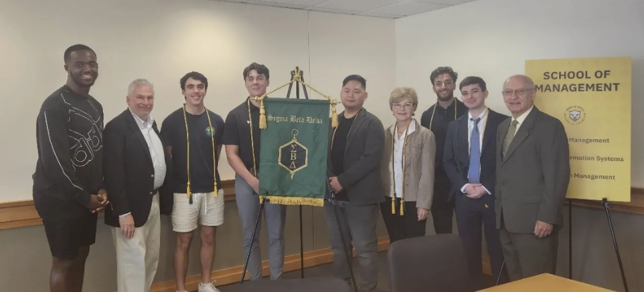 students and professors standing in front of a long table