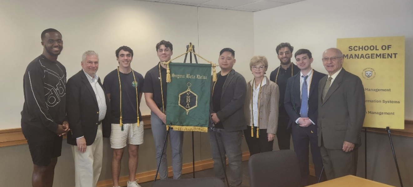 students and professors standing in front of a long table