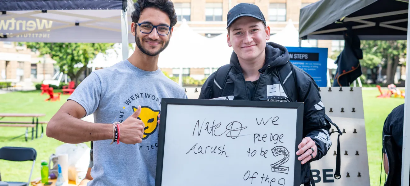 two students hold up a sign