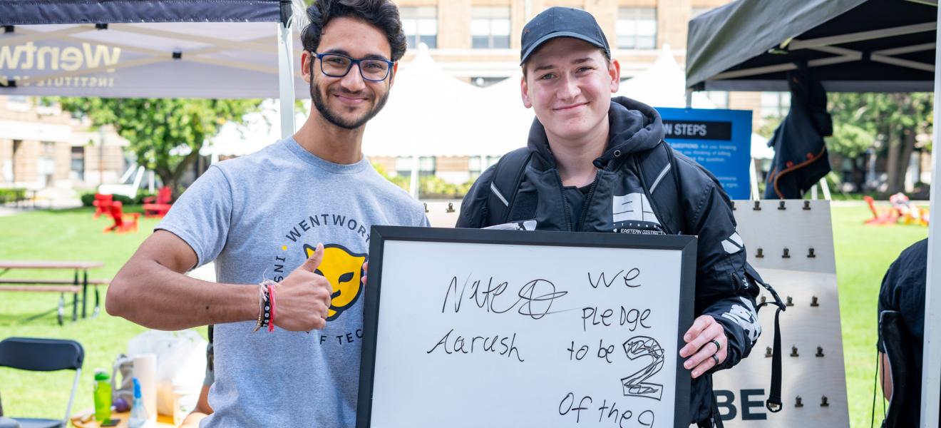 two students hold up a sign