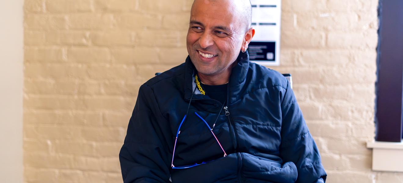 a man smiles while seated in a classroom
