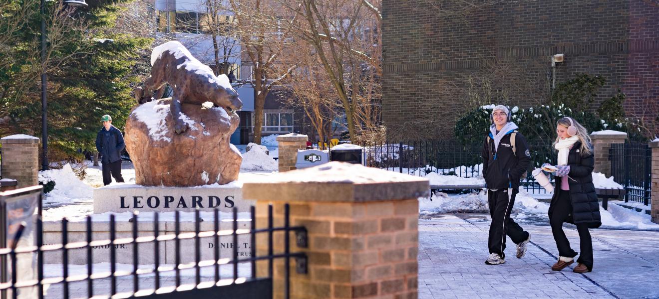 a leopard statue and students walking in the winter