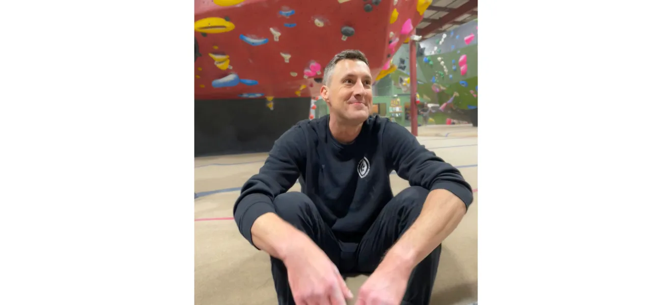 a man sitting on the floor of a rock climbing gym