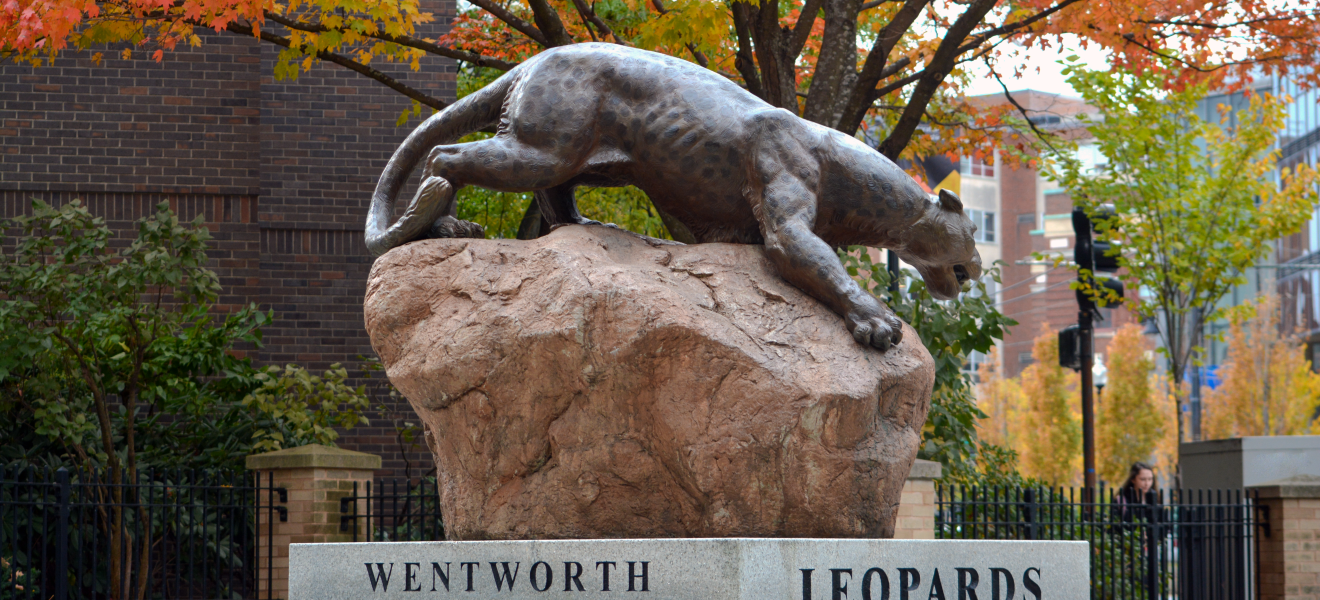 a statue of a leopard surrounded by autumn leaves