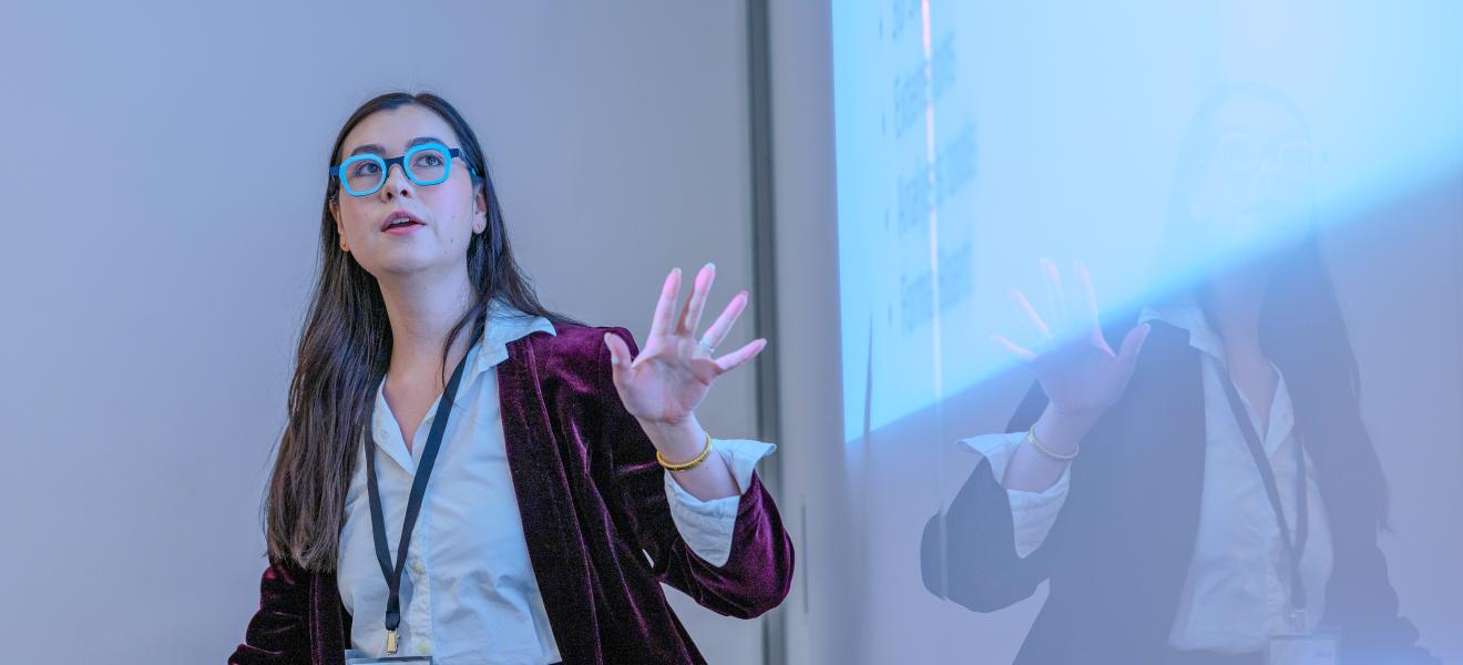 a woman speaking in front of a projection
