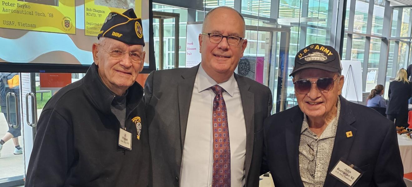 three men pose for a camera with two in military veteran dress