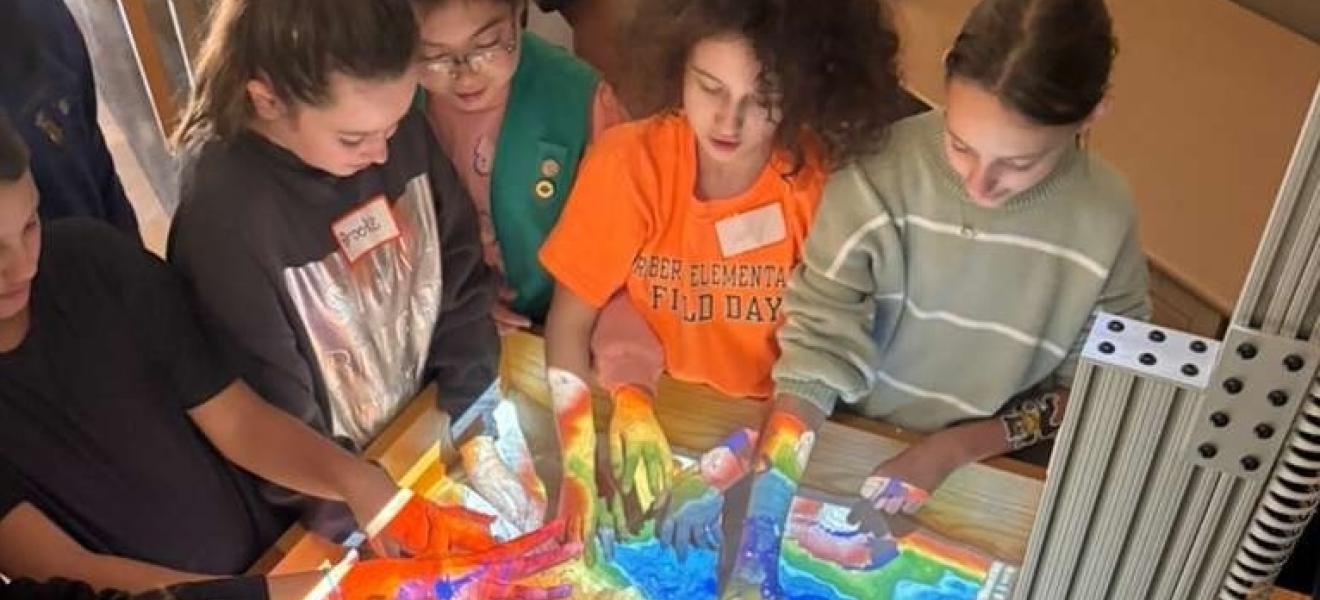 a group of girl scouts interact with an augmented reality teaching device