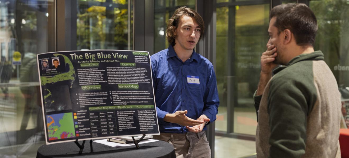a student shows off an ai-related project to attendees of an event
