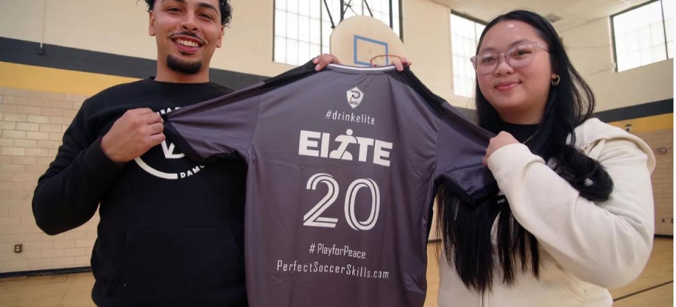 two people hold up an athletic shirt that reads "elite"