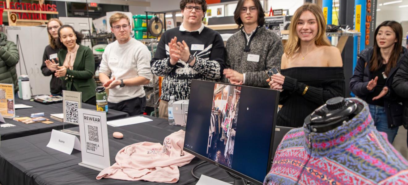 a group of students pose for a photo in front of clothing and other created materials