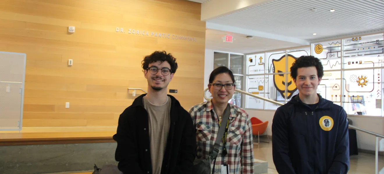 three people pose for the camera in an atrium area