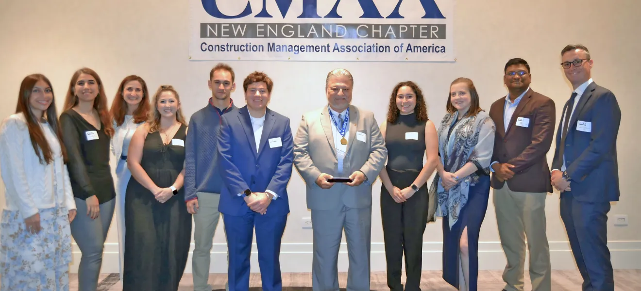 A group of people pose around a man holding an award