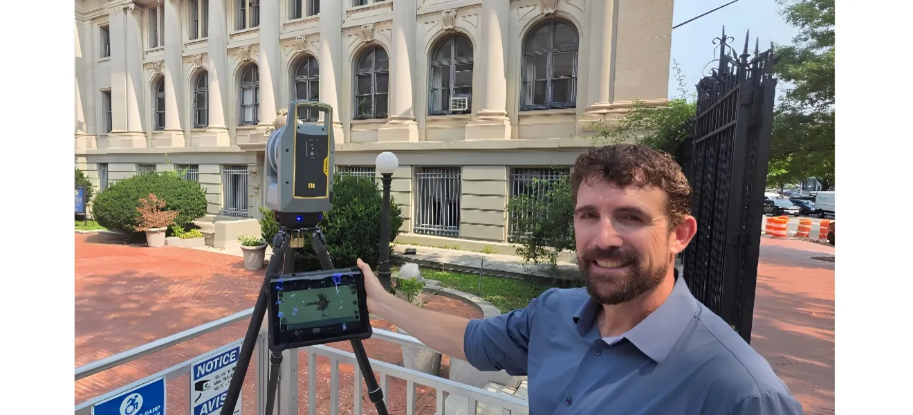 a man stands with a 3d scanner in front of a beaux-arts style building