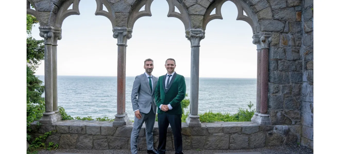two men standing in front of large windows overlooking the water