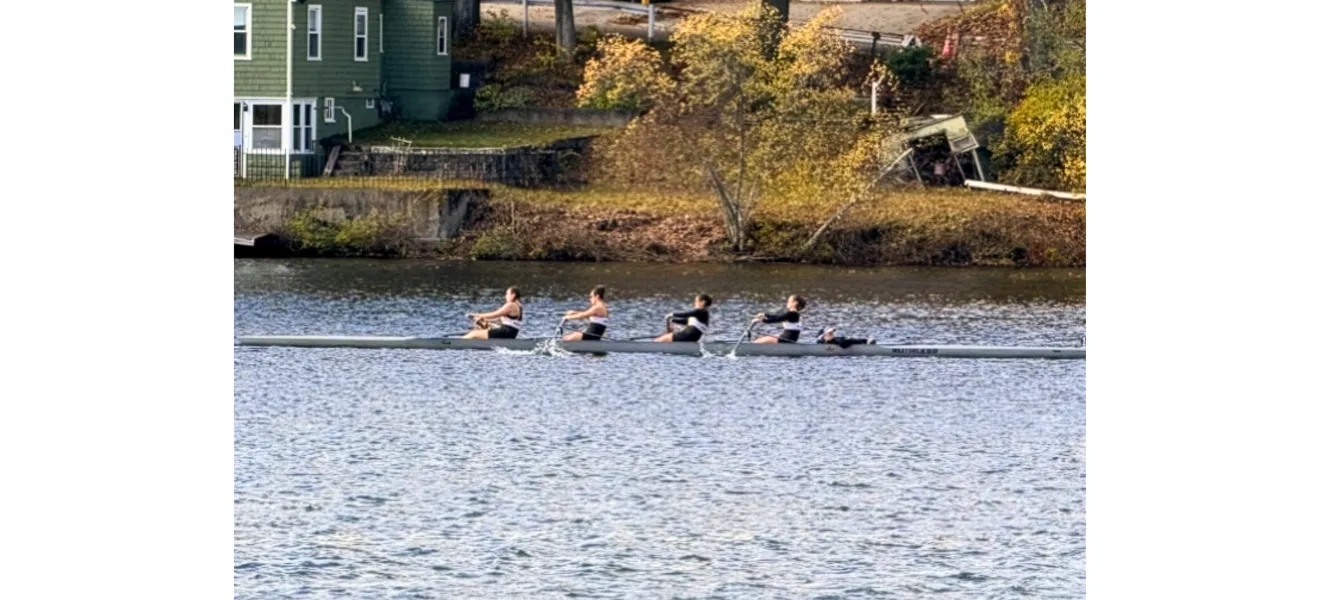 four women in a boat rowing on the river
