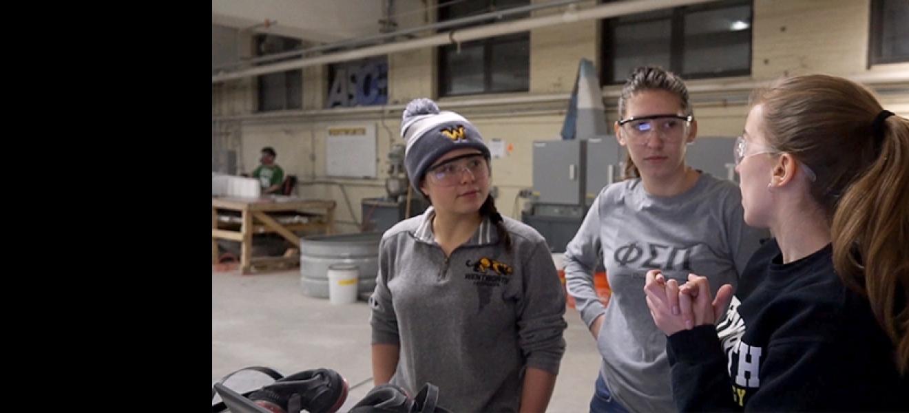 Three female students discussing strategy for building concrete canoe.