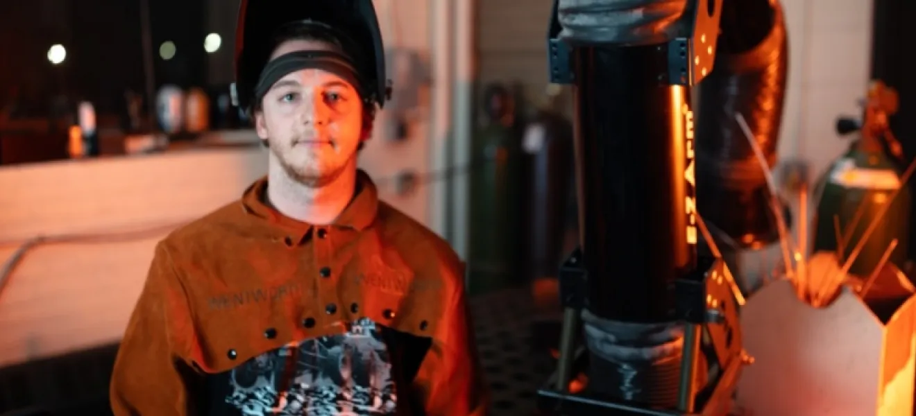 student posing in welders hat and gear