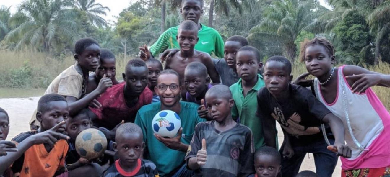 group of children and one man holding a soccer ball