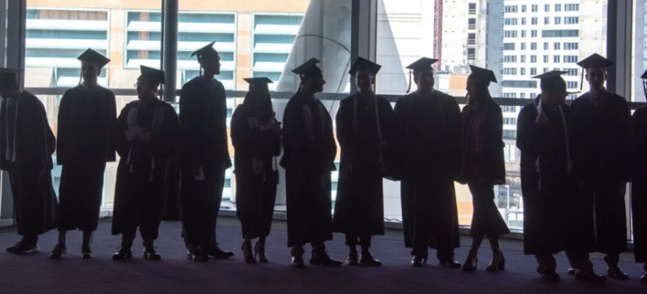 students graduates standing in front of a window