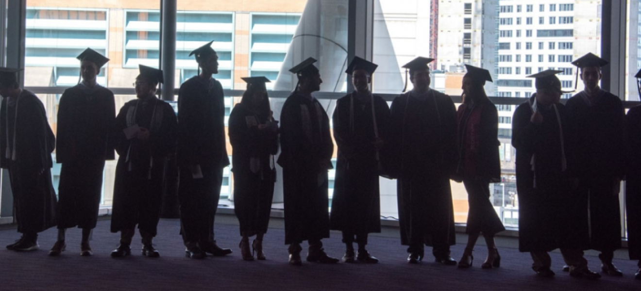 students graduates standing in front of a window