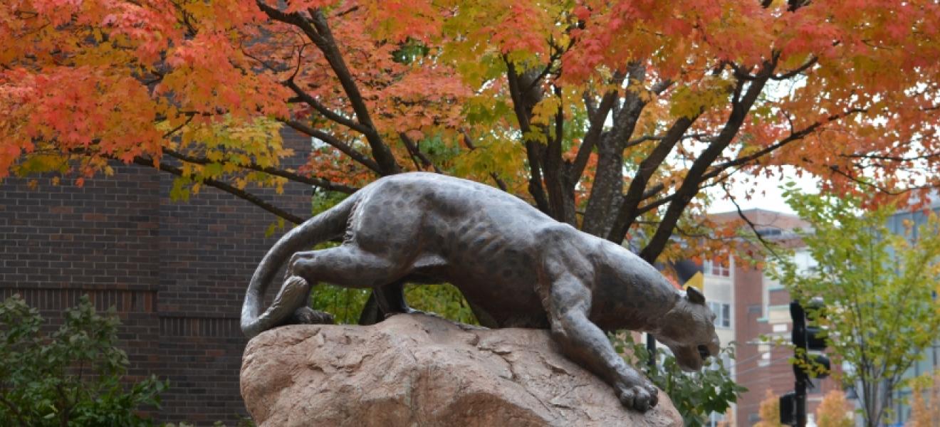 a leopard statue in front of orange leaves