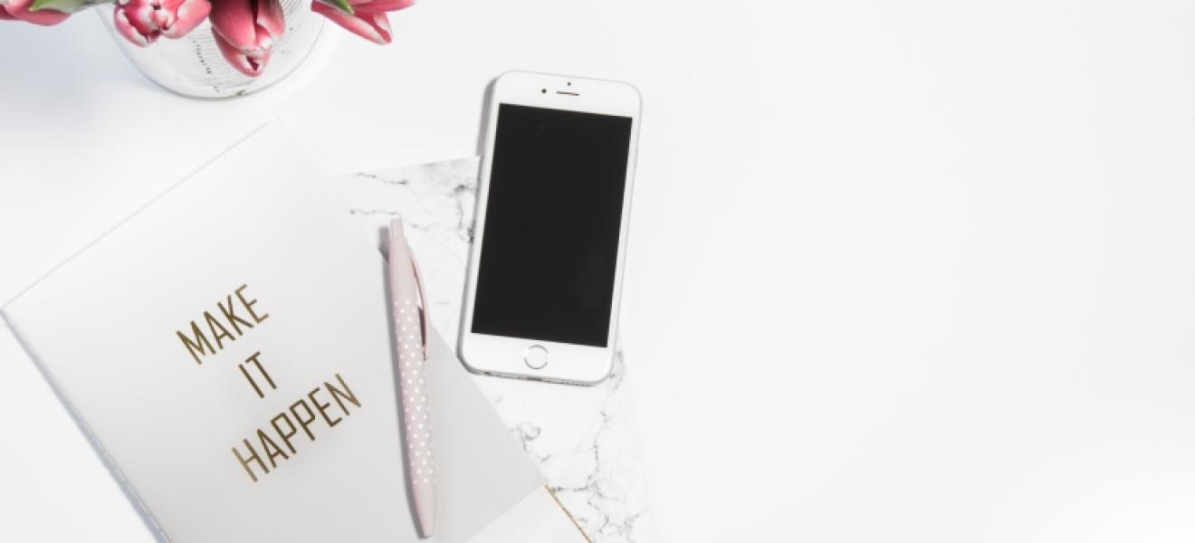 A pen, card, iPhone and roses on a table