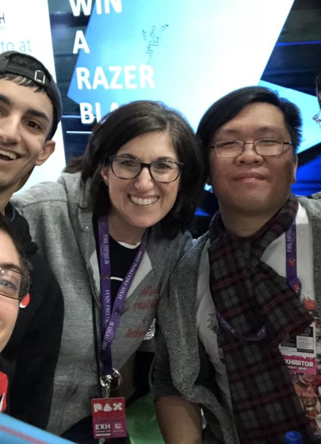 Hollis Greenberg poses with four students with a powerpoint displaying in the background