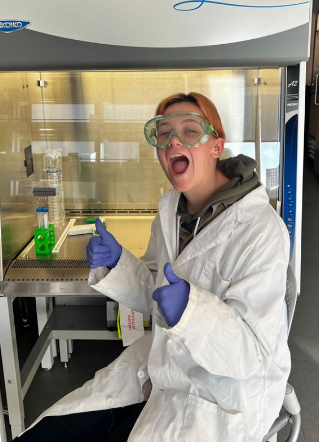 Jessica Rowe smiles in the lab while working on an experiment