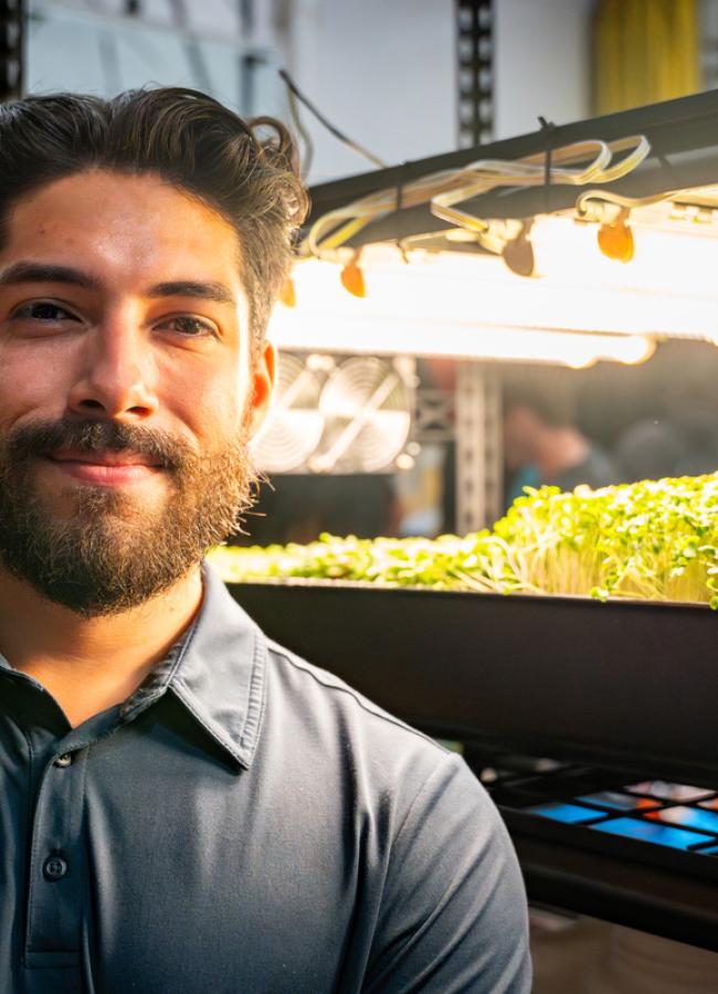 Daniel Mejia-Raminho stands in front of his microgreen capstone project.