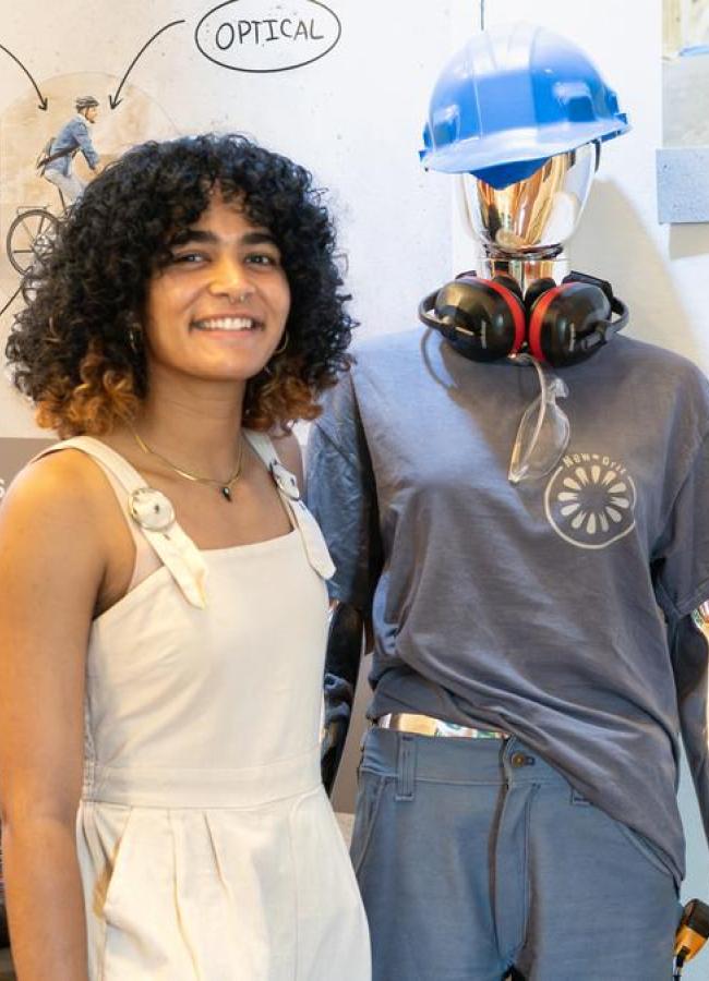 Zoe Graham stands in front of her workwear designed for female bodies called "New Grit"