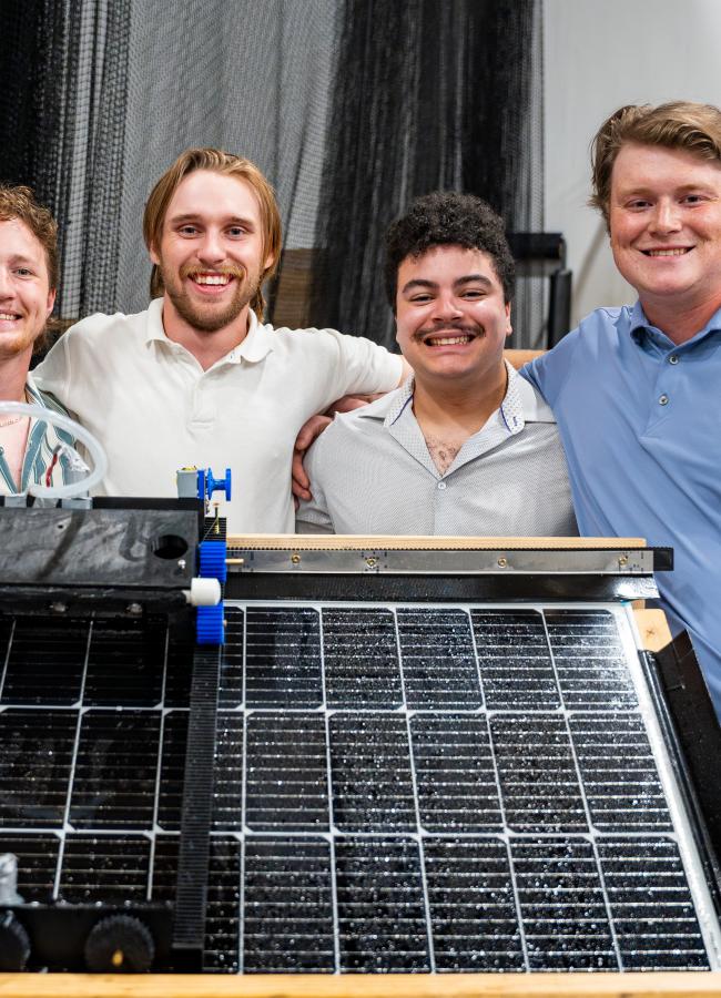 students stand behind a solar panel